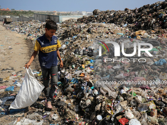 A Palestinian boy is searching for recyclables at a garbage dump in Deir el-Balah, in the central Gaza Strip, on June 13, 2024, amid the ong...