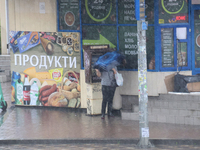 A woman is hiding under an umbrella during heavy rain, which is amounting to half of the monthly average, in Kyiv, Ukraine, on June 12, 2024...