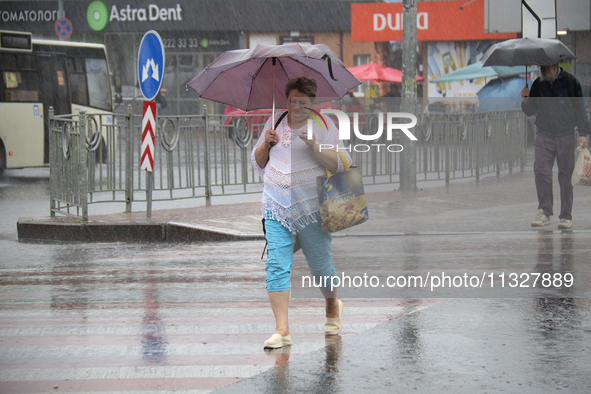 A woman is walking under an umbrella as she is crossing a street during heavy rain, which is amounting to half of the monthly average, in Ky...