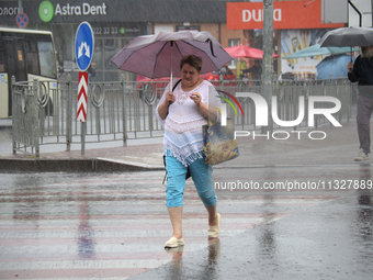 A woman is walking under an umbrella as she is crossing a street during heavy rain, which is amounting to half of the monthly average, in Ky...