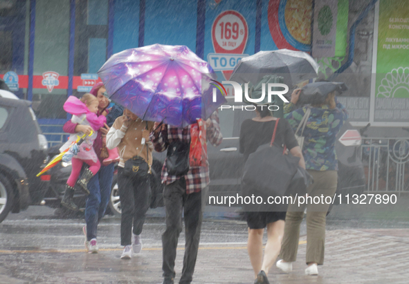 Pedestrians are walking under umbrellas during heavy rain, which is amounting to half of the monthly average, in Kyiv, Ukraine, on June 12,...