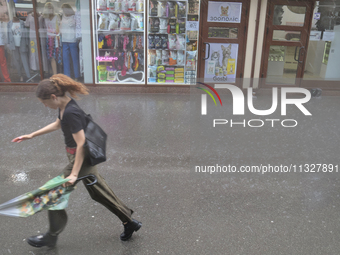 A woman is running under heavy rain, which is amounting to half of the monthly average, in Kyiv, Ukraine, on June 12, 2024. (