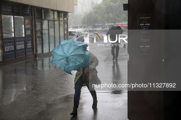 Strong gusts of wind are bending an umbrella of a woman during heavy rain, which is amounting to half of the monthly average, in Kyiv, Ukrai...