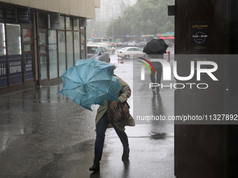 Strong gusts of wind are bending an umbrella of a woman during heavy rain, which is amounting to half of the monthly average, in Kyiv, Ukrai...