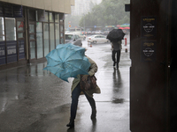 Strong gusts of wind are bending an umbrella of a woman during heavy rain, which is amounting to half of the monthly average, in Kyiv, Ukrai...