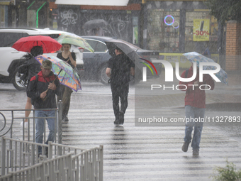 People are crossing a street with umbrellas during heavy rain, which is amounting to half of the monthly average, in Kyiv, Ukraine, on June...