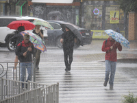 People are crossing a street with umbrellas during heavy rain, which is amounting to half of the monthly average, in Kyiv, Ukraine, on June...