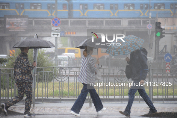 Pedestrians are walking under umbrellas during heavy rain, which is amounting to half of the monthly average, in Kyiv, Ukraine, on June 12,...