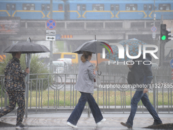 Pedestrians are walking under umbrellas during heavy rain, which is amounting to half of the monthly average, in Kyiv, Ukraine, on June 12,...