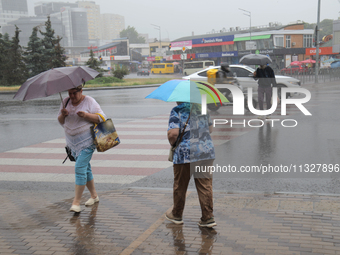 Pedestrians are walking under umbrellas during heavy rain, which is amounting to half of the monthly average, in Kyiv, Ukraine, on June 12,...