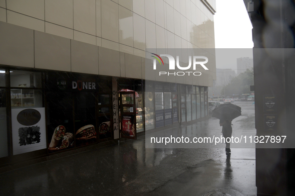 A woman is walking with an umbrella along a street during heavy rain, which is amounting to half of the monthly average, in Kyiv, Ukraine, o...