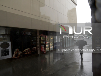 A woman is walking with an umbrella along a street during heavy rain, which is amounting to half of the monthly average, in Kyiv, Ukraine, o...