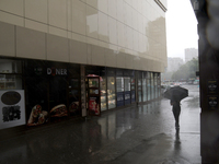 A woman is walking with an umbrella along a street during heavy rain, which is amounting to half of the monthly average, in Kyiv, Ukraine, o...