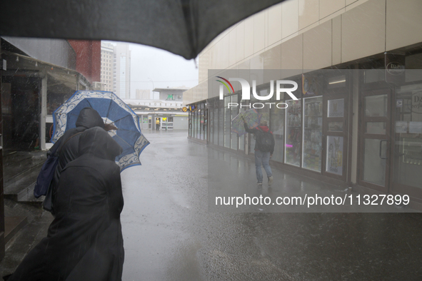 People are walking along a street with umbrellas during heavy rain, which is amounting to half of the monthly average, in Kyiv, Ukraine, on...