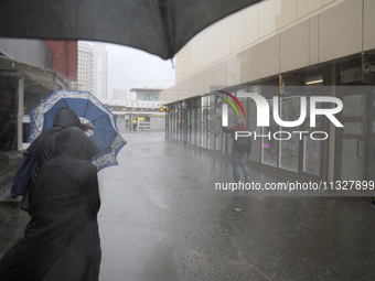 People are walking along a street with umbrellas during heavy rain, which is amounting to half of the monthly average, in Kyiv, Ukraine, on...