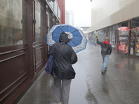 People are walking along a street with umbrellas during heavy rain, which is amounting to half of the monthly average, in Kyiv, Ukraine, on...