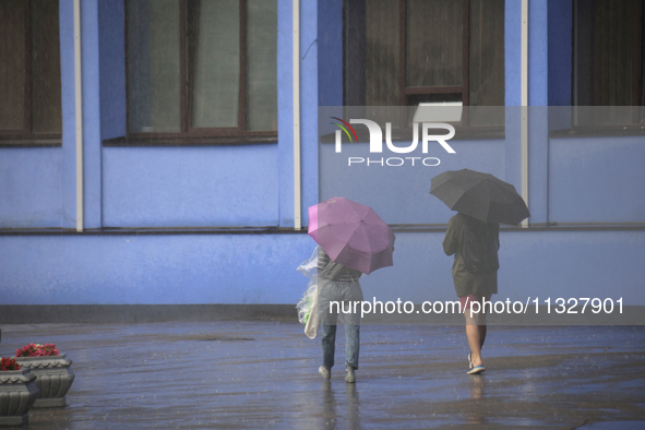 People are walking along a street with umbrellas during heavy rain, which is amounting to half of the monthly average, in Kyiv, Ukraine, on...