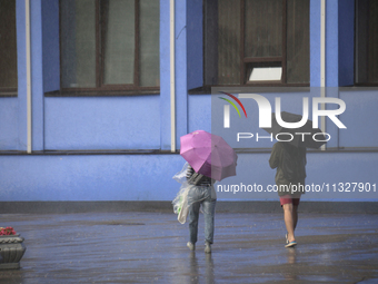 People are walking along a street with umbrellas during heavy rain, which is amounting to half of the monthly average, in Kyiv, Ukraine, on...