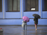 People are walking along a street with umbrellas during heavy rain, which is amounting to half of the monthly average, in Kyiv, Ukraine, on...