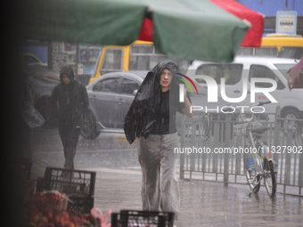 A woman is covering her head with a jacket during heavy rain, which has amounted to half of the monthly average, in Kyiv, Ukraine, on June 1...