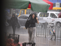 A woman is covering her head with a jacket during heavy rain, which has amounted to half of the monthly average, in Kyiv, Ukraine, on June 1...