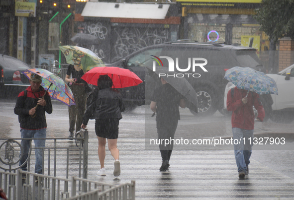 People are crossing a street with umbrellas during heavy rain, which is amounting to half of the monthly average, in Kyiv, Ukraine, on June...