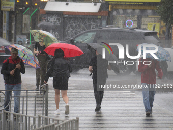 People are crossing a street with umbrellas during heavy rain, which is amounting to half of the monthly average, in Kyiv, Ukraine, on June...