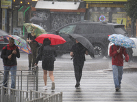 People are crossing a street with umbrellas during heavy rain, which is amounting to half of the monthly average, in Kyiv, Ukraine, on June...