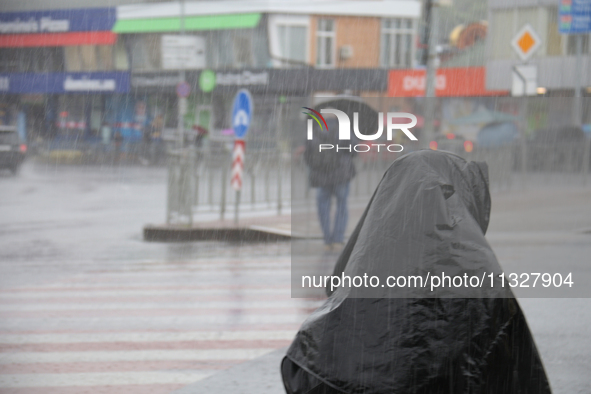 A woman is covering her head with a jacket during heavy rain, which has amounted to half of the monthly average, in Kyiv, Ukraine, on June 1...