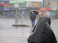 A woman is covering her head with a jacket during heavy rain, which has amounted to half of the monthly average, in Kyiv, Ukraine, on June 1...