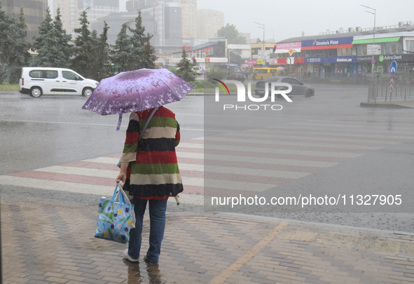 A woman is walking under an umbrella during heavy rain, which is amounting to half of the monthly average, in Kyiv, Ukraine, on June 12, 202...