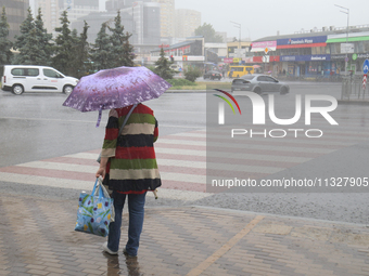 A woman is walking under an umbrella during heavy rain, which is amounting to half of the monthly average, in Kyiv, Ukraine, on June 12, 202...