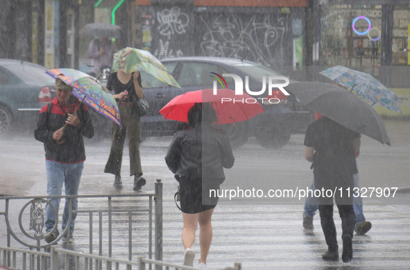 People are crossing a street with umbrellas during heavy rain, which is amounting to half of the monthly average, in Kyiv, Ukraine, on June...