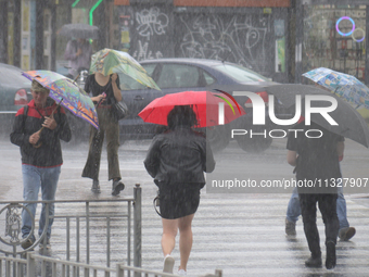 People are crossing a street with umbrellas during heavy rain, which is amounting to half of the monthly average, in Kyiv, Ukraine, on June...