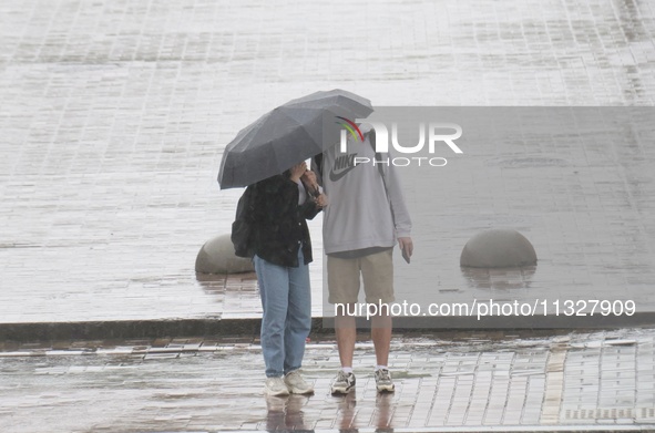 A man and woman are sharing an umbrella during heavy rain, which is amounting to half of the monthly average, in Kyiv, Ukraine, on June 12,...