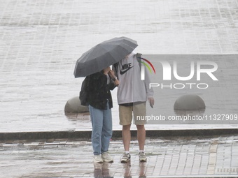 A man and woman are sharing an umbrella during heavy rain, which is amounting to half of the monthly average, in Kyiv, Ukraine, on June 12,...