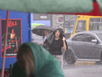 A woman is covering her head with a jacket during heavy rain, which has amounted to half of the monthly average, in Kyiv, Ukraine, on June 1...