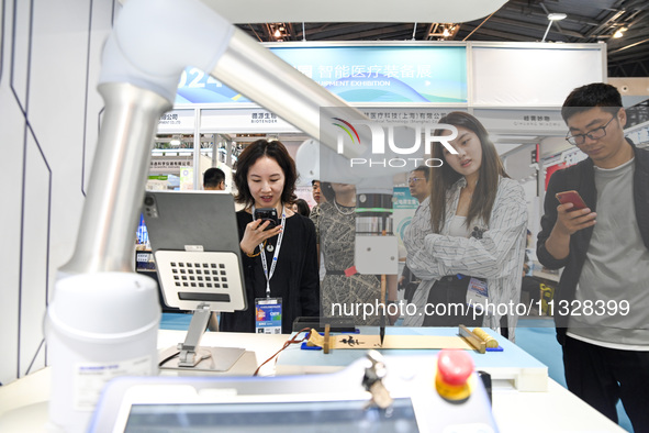 Visitors are watching a calligraphy robot write at The 10th China (Shanghai) International Technology Fair in Shanghai, China, on June 13, 2...