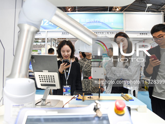 Visitors are watching a calligraphy robot write at The 10th China (Shanghai) International Technology Fair in Shanghai, China, on June 13, 2...