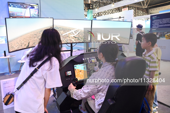 Visitors are experiencing a flight simulation simulator at The 10th China (Shanghai) International Technology Fair in Shanghai, China, on Ju...