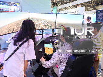 Visitors are experiencing a flight simulation simulator at The 10th China (Shanghai) International Technology Fair in Shanghai, China, on Ju...