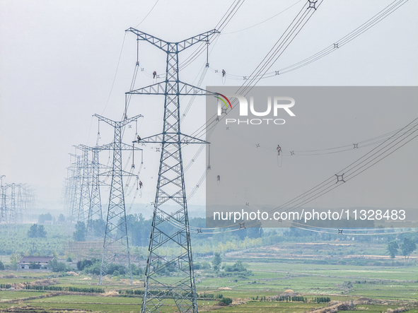 Power supply workers are carrying out acceptance work on a new 500-kilovolt transmission line in Nanjing, Jiangsu province, China, on June 1...