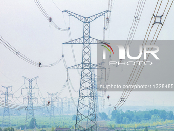 Power supply workers are carrying out acceptance work on a new 500-kilovolt transmission line in Nanjing, Jiangsu province, China, on June 1...