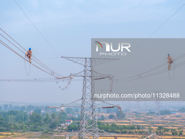 Power supply workers are carrying out acceptance work on a new 500-kilovolt transmission line in Nanjing, Jiangsu province, China, on June 1...