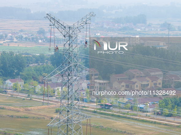 Power supply workers are carrying out acceptance work on a new 500-kilovolt transmission line in Nanjing, Jiangsu province, China, on June 1...