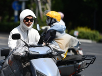 Citizens are wearing sun-protective clothing and riding on a street under high temperatures in Fuyang, China, on June 14, 2024. (