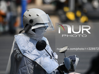 Citizens are wearing sun-protective clothing and riding on a street under high temperatures in Fuyang, China, on June 14, 2024. (