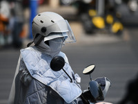 Citizens are wearing sun-protective clothing and riding on a street under high temperatures in Fuyang, China, on June 14, 2024. (