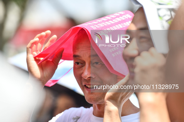 Citizens are wearing sun-protective clothing and riding on a street under high temperatures in Fuyang, China, on June 14, 2024. 