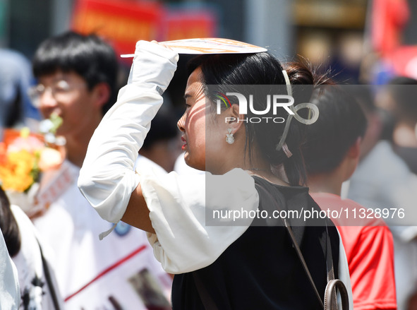 Citizens are wearing sun-protective clothing and riding on a street under high temperatures in Fuyang, China, on June 14, 2024. 